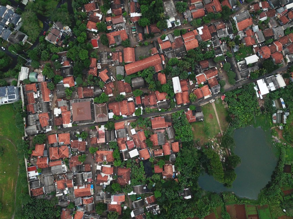 Aerial view of a community, showing houses, roads, green areas, and a lake.