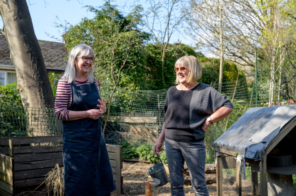 Two smiling women in a community garden