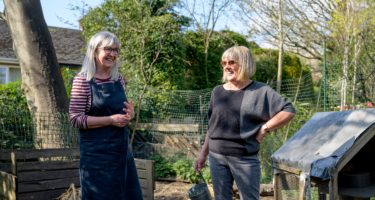 Two smiling women in a community garden