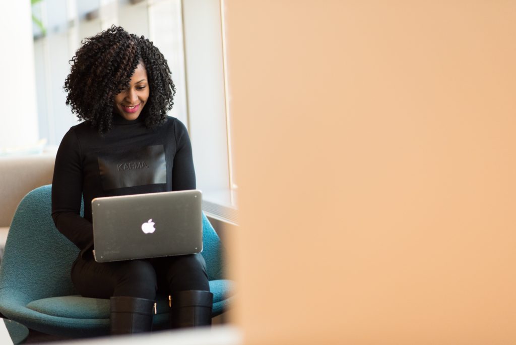 Woman smiling and looking at a laptop screen.