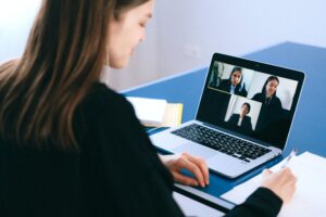 A woman using a laptop on a call with three stakeholders.