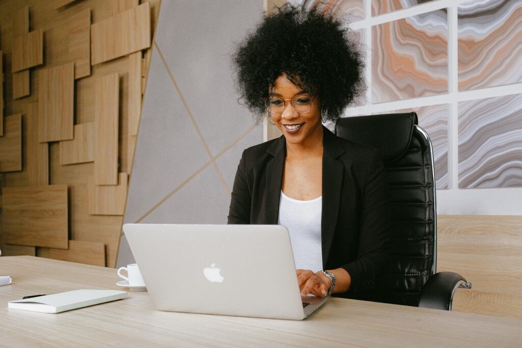 Smiling woman sitting at a desk in front of a laptop.