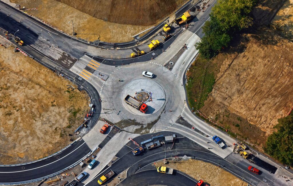 Birds eye view of a large highway intersection with trucks and construction vehicles.