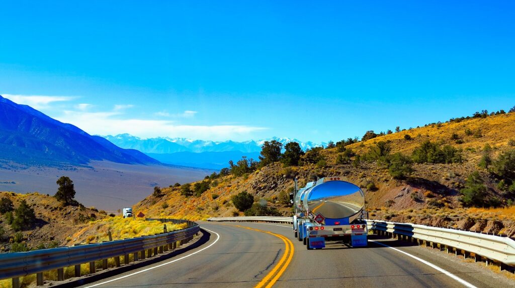 Truck driving along highway in mountainous region.