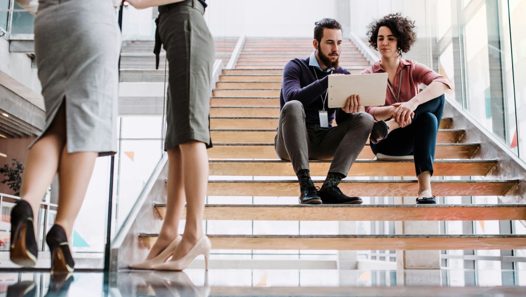 People sitting on stairs with a laptop, in discussion.