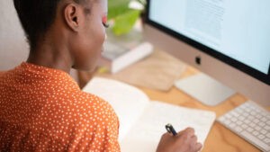 Person sitting at a computer writing a list.