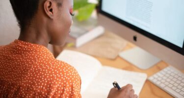 Person sitting at a computer writing a list.