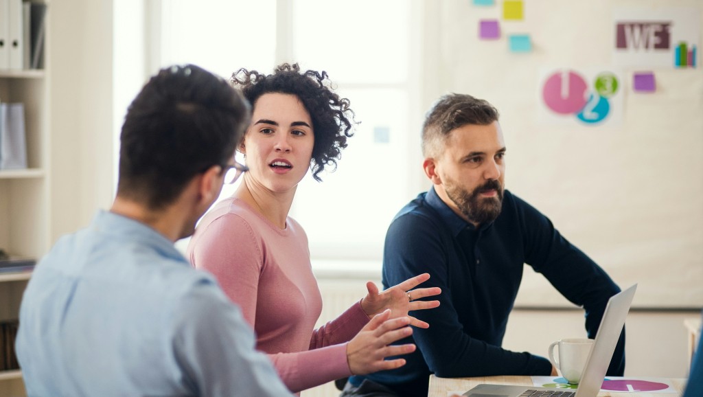 Colleagues discussing an issue at a desk.