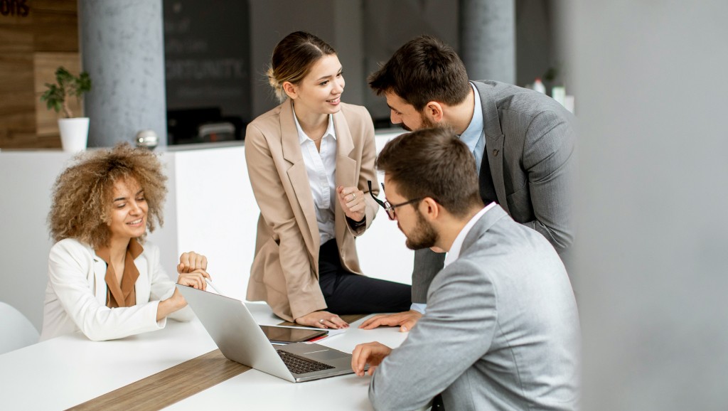 Four people sitting or standing at a table, discussing stakeholder requirements for a project.