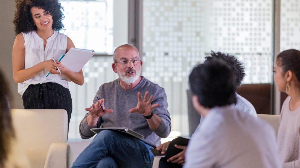 People in a meeting with a man explaining things to a group