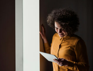 Woman looking down and smiling at device.