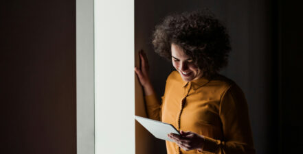 Woman looking down and smiling at device.