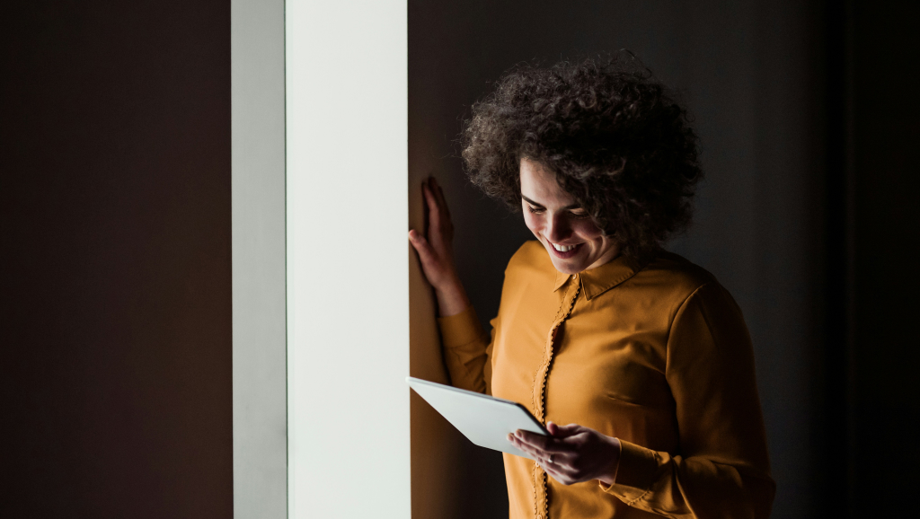 Woman looking down and smiling at device.