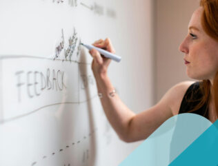 Woman writing the word "feedback" on a whiteboard.