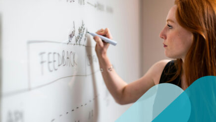 Woman writing the word "feedback" on a whiteboard.