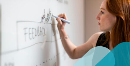 Woman writing the word "feedback" on a whiteboard.