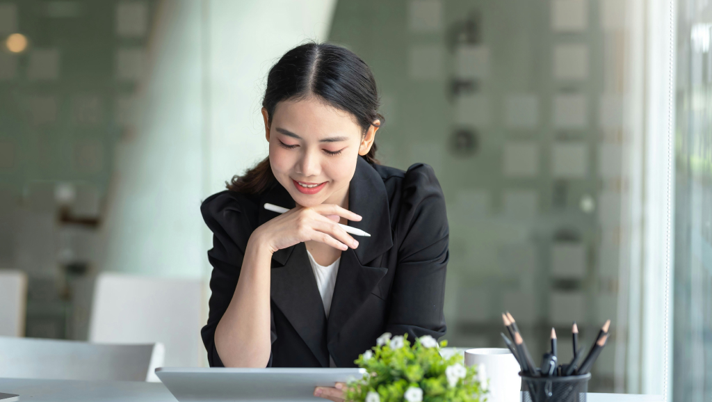 A corporate woman smiles while holding a stylus and tablet.