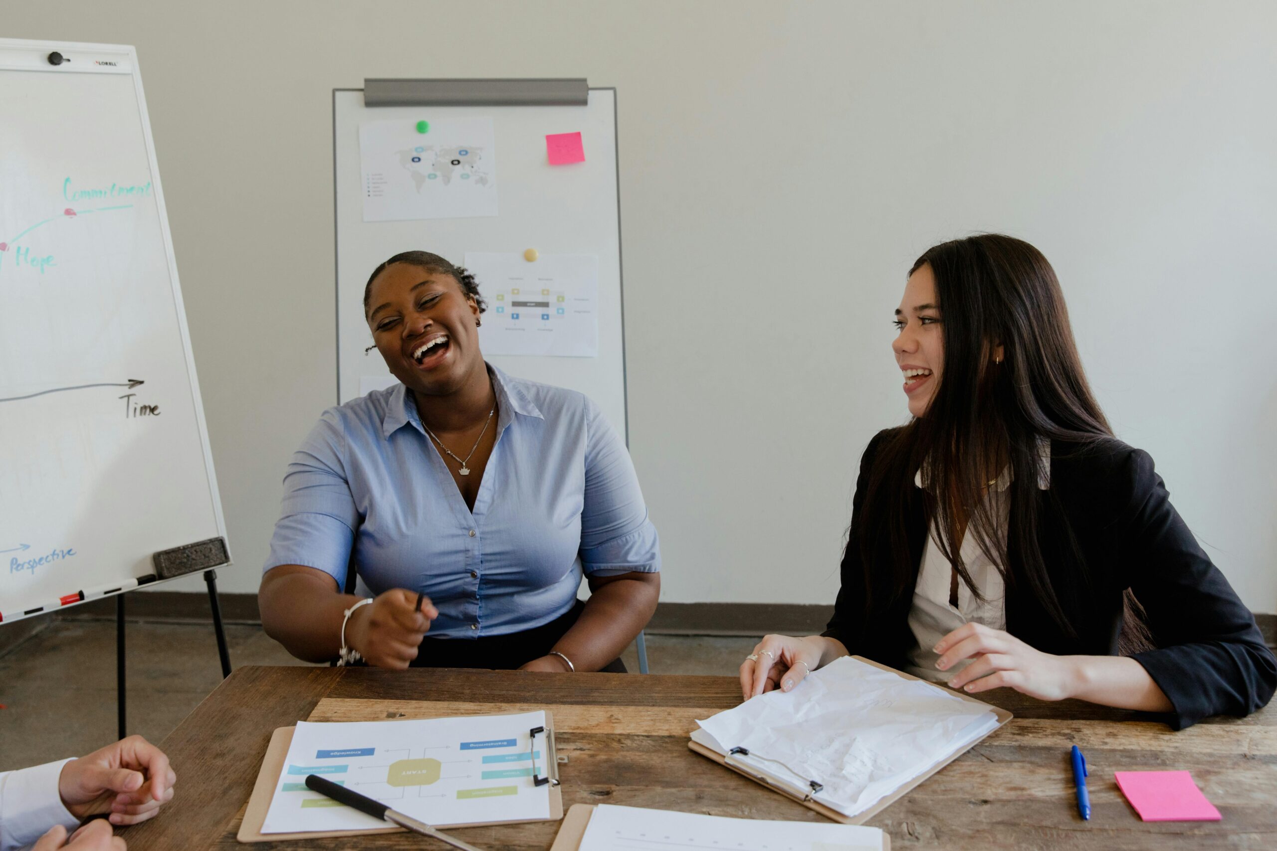 Two women chatting and laughing in a planning meeting.