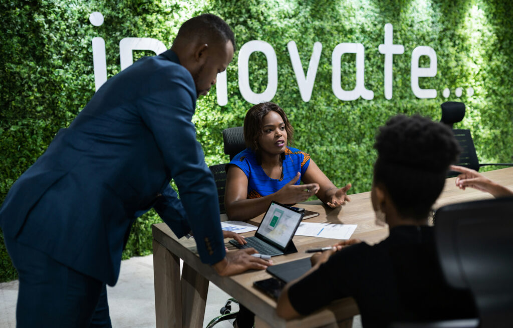 Team of young business people having a meeting against a living wall with the word ‘innovate’ written across it.