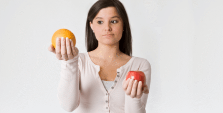 Image of person comparing an apple with an orange