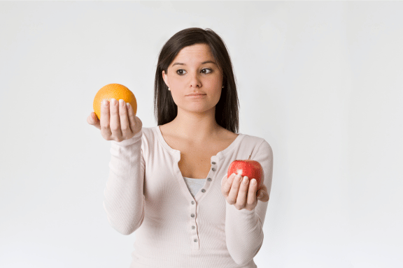 Image of person comparing an apple with an orange