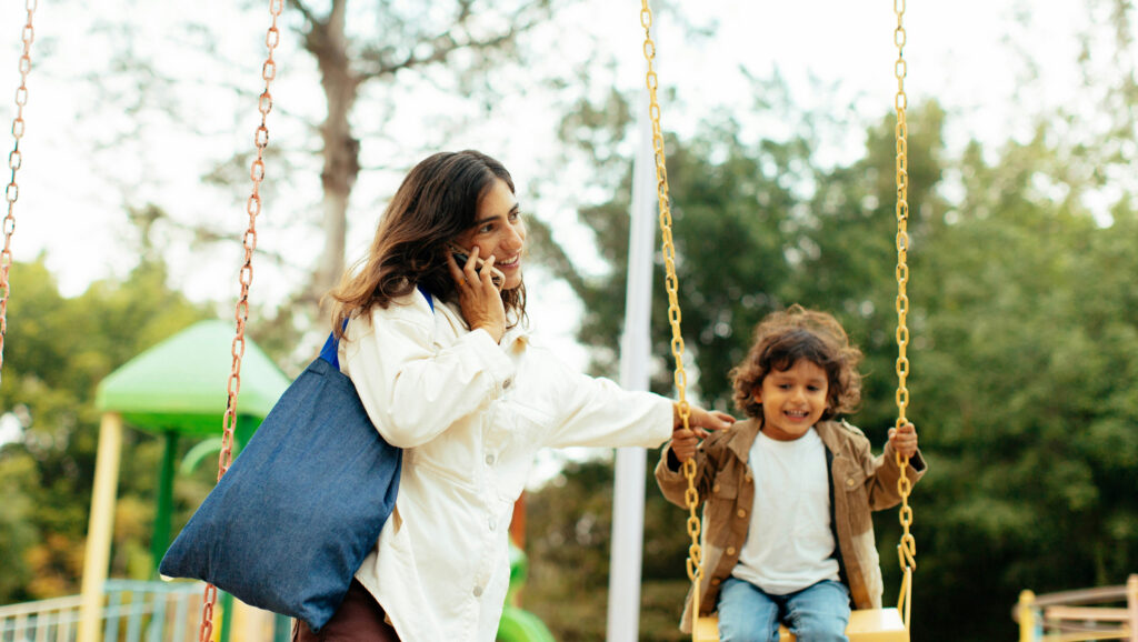 Caregiver pushing child on swing to represent local government and childcare duties