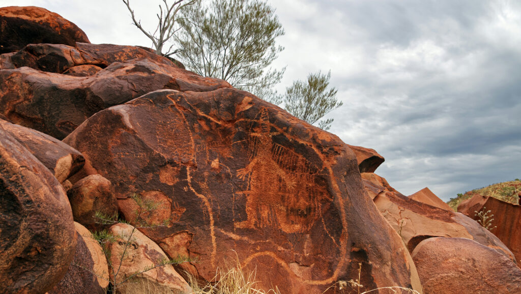 Large rock with Indigenous-style artwork or markings on it.