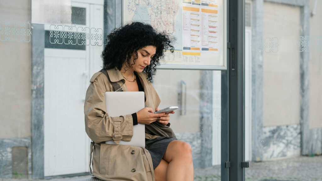 Woman at bus stop using CzRM software to check bus times.