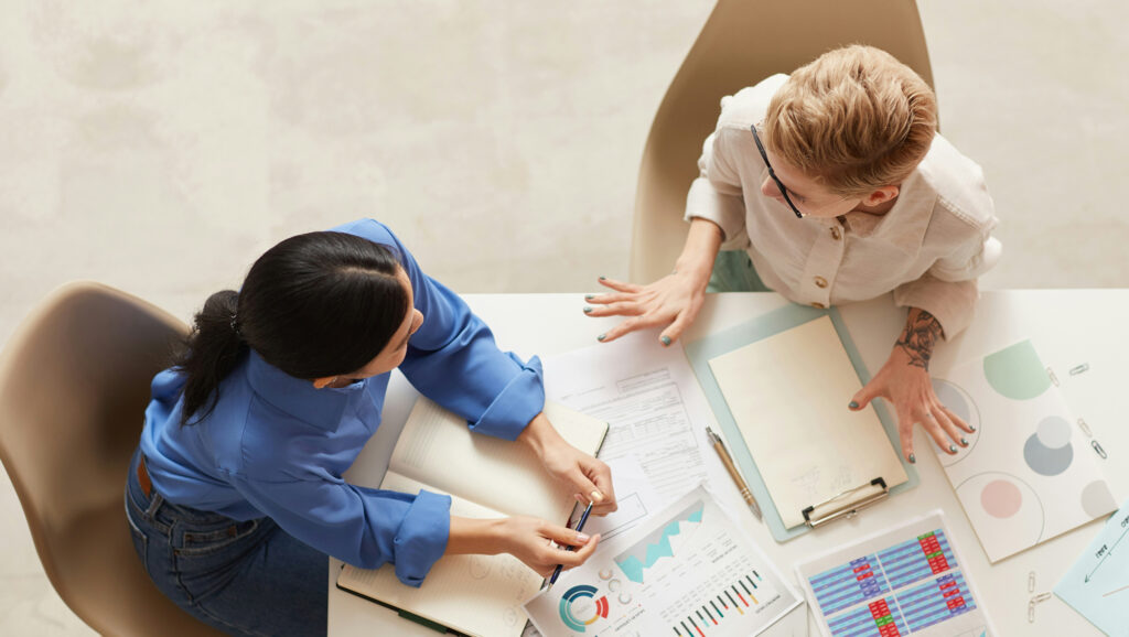 Overhead photo of two people in an office setting having a meeting.