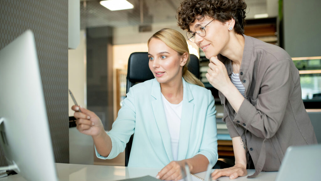 Two businesswomen looking at a computer screen. The image represents choosing stakeholder software.